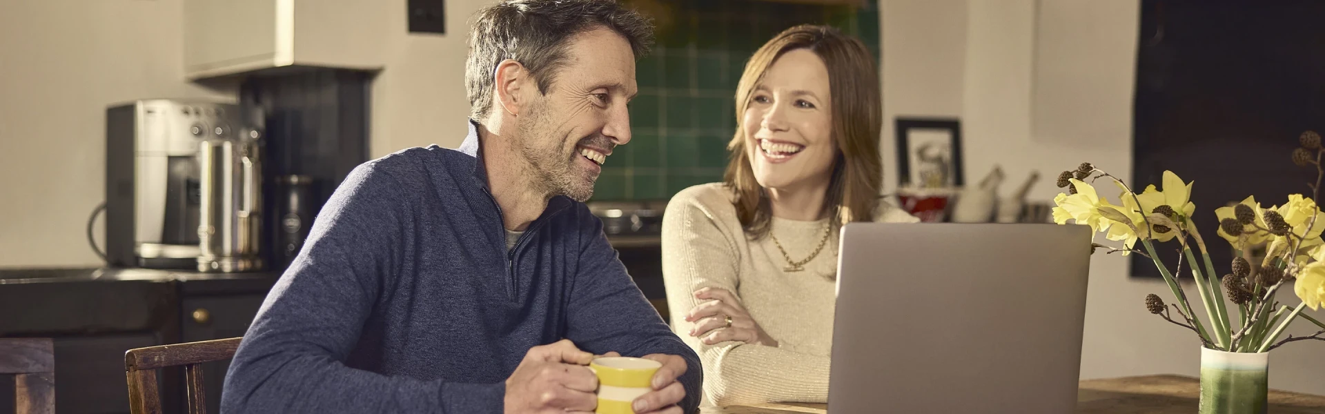 Couple smiling while using a laptop together at home