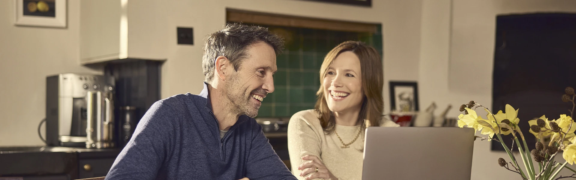 Couple smiling while using a laptop together at home
