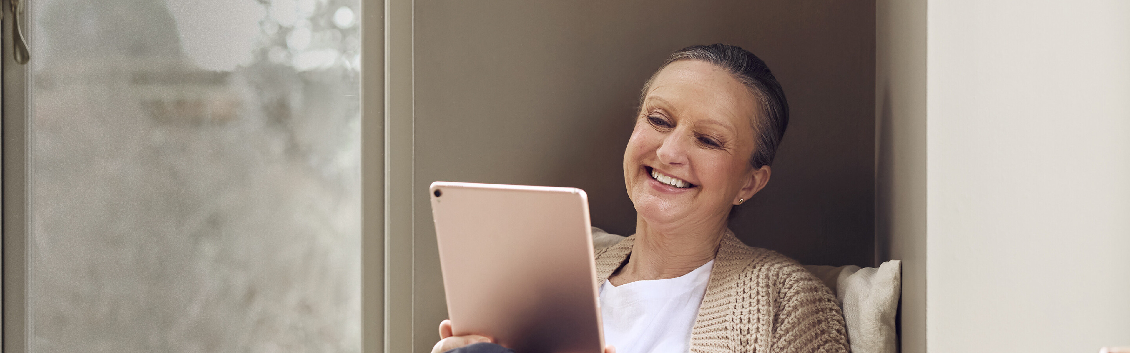 happy woman smiling at tablet streaming internet