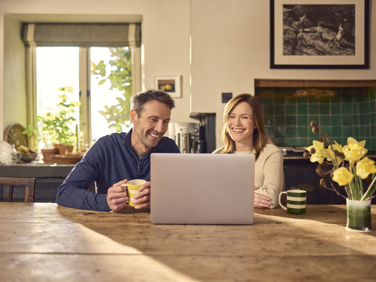 Couple video calling in the kitchen on a laptop