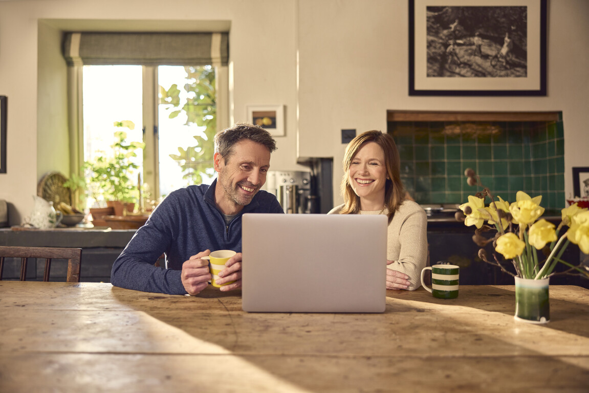 Couple video calling in the kitchen on a laptop