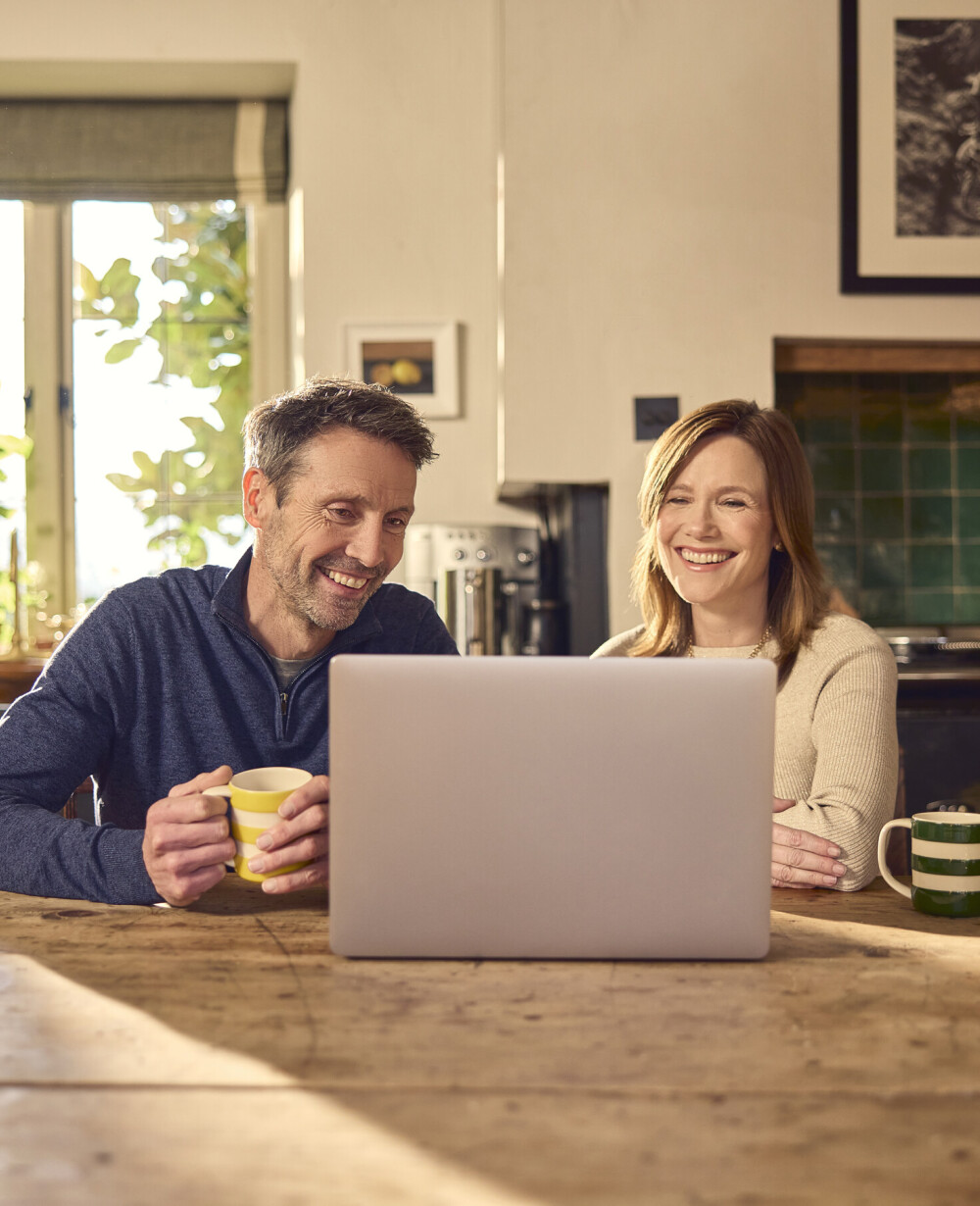 Couple video calling in the kitchen on a laptop