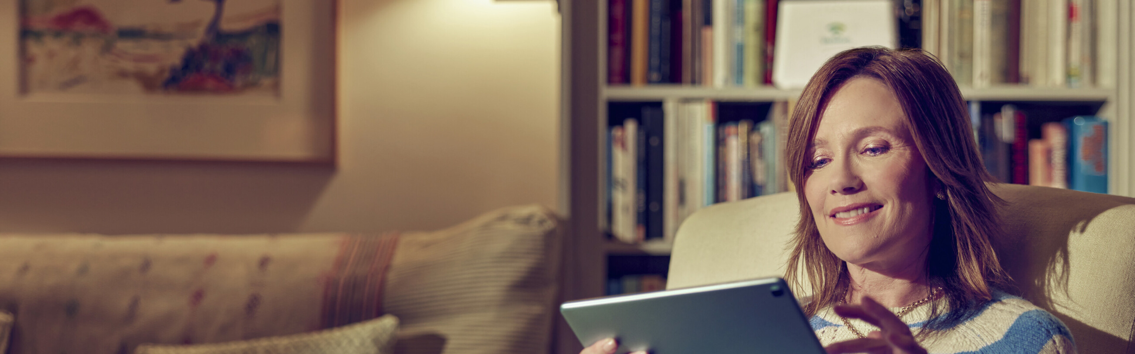 Woman sitting on sofa surfing the internet with a tablet