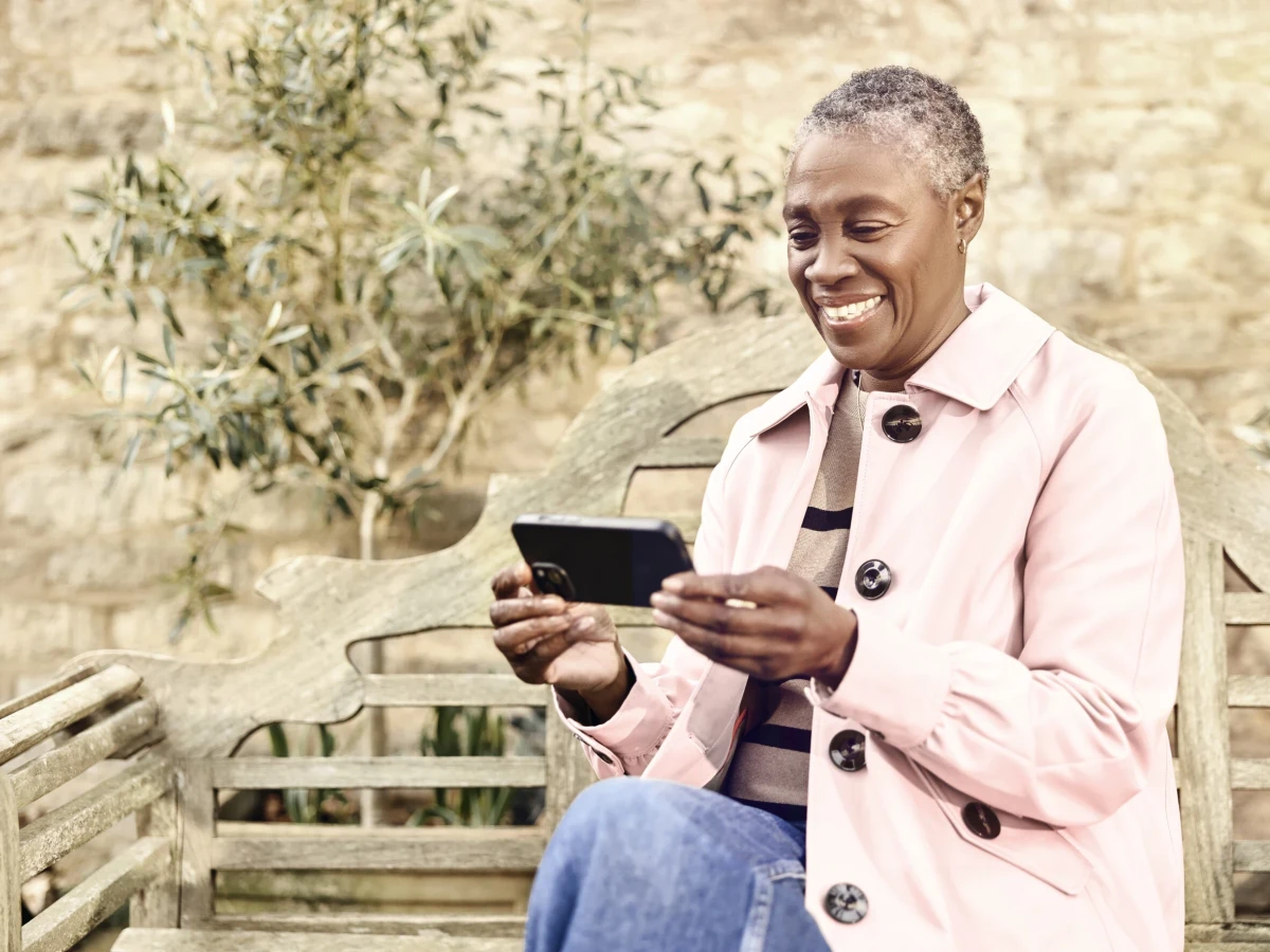 Woman using a smartphone with Voneus WiFi Mesh at home in the garden