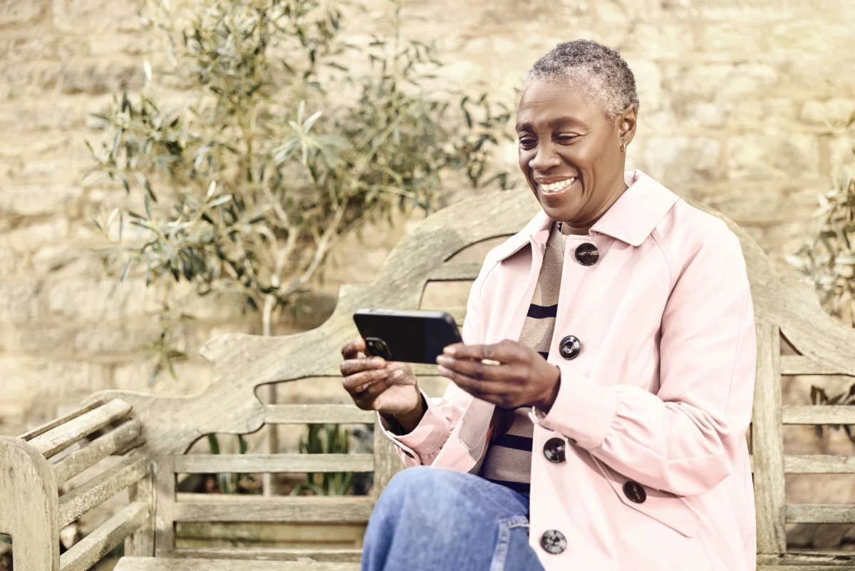 Woman using a smartphone with Voneus WiFi Mesh at home in the garden
