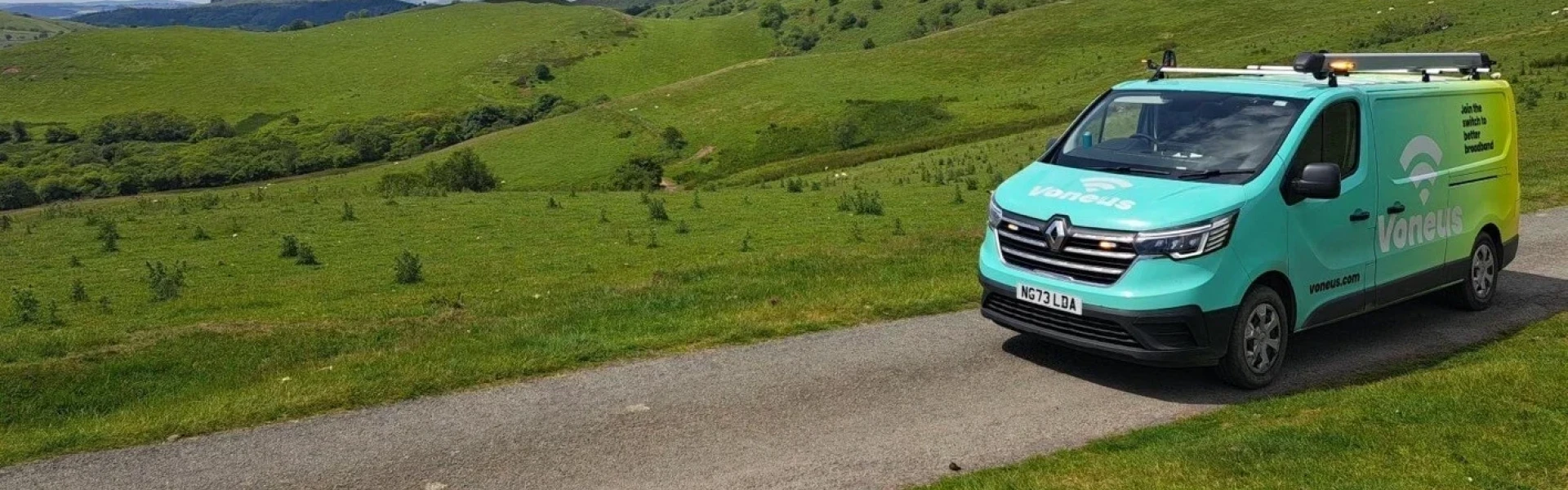 Green Voneus broadband van parked on a country road with open grassy hills in the background in Devon