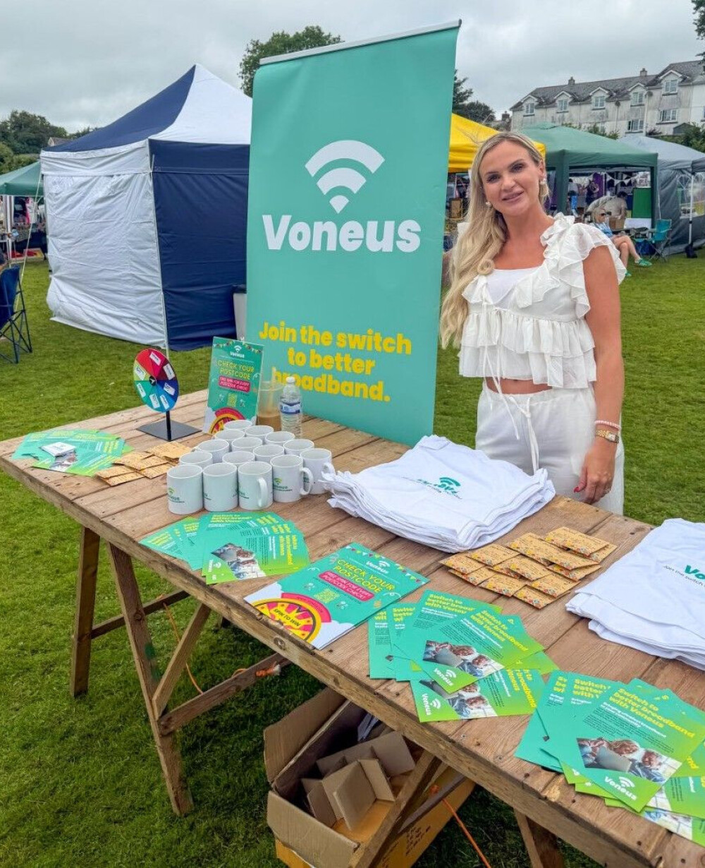 A Voneus staff member stood behind a table of Voneus broadband merchandise and information at the Tamar Valley Fete