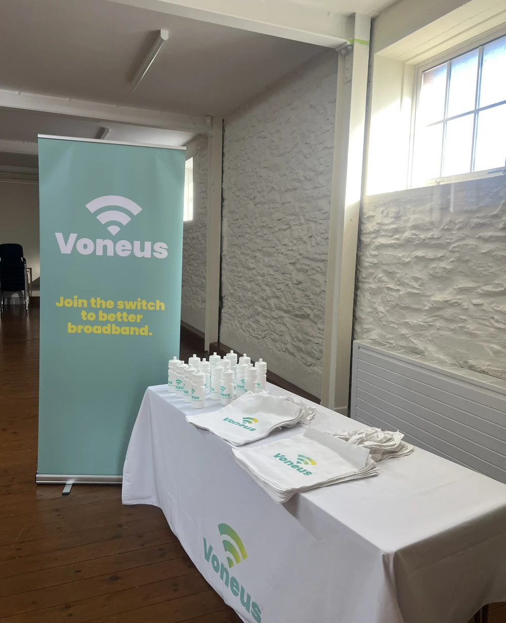 Voneus broadband information stand at Ambleston Memorial Hall, featuring branded merchandise for a local community event.