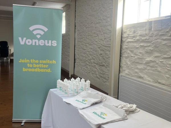 Voneus Broadband promotional stand featuring branded reusable bags, water bottles and a banner, showcasing broadband services for Pontesbury and Stiperstones residents.